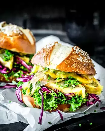 Der Schriftzug „Burger” auf einem Foto von einem Maultaschenburger mit Laugenbrötchen.