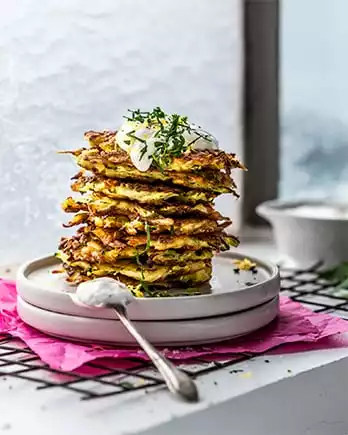 Der Schriftzug „Daily Boom” auf einem Foto mit Zucchinipuffern.