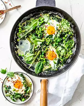 Der Schriftzug „leicht & gesund” auf einem Foto einer grünen Shakshuka mit Ei in einer Pfanne.