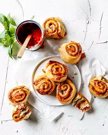 Der Schriftzug „Snacks & Fingerfood” auf einem Foto von Pizzaschnecken.